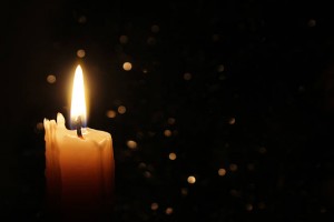 White Candles Burning in the Dark with focus on single candle in foreground.